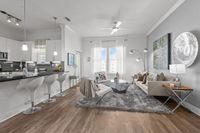 Modern apartment interior with an open-concept living room and kitchen, featuring sleek bar stools, contemporary lighting, and stylish decor.