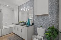 Contemporary bathroom with elegant gray mosaic tiles, sleek white cabinetry, and modern fixtures, creating a serene spa-like atmosphere.