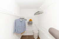 Spacious walk-in closet featuring sleek white shelving, hanging space for clothes, and a stylish hat on display, perfect for organized living.