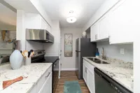 Modern kitchen with sleek granite countertops, stainless steel appliances, and elegant white cabinetry for a stylish cooking experience.