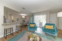Modern living room with teal armchairs, elegant decor, and an open-plan kitchen perfect for entertainment.