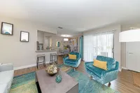 Contemporary living area with vibrant teal chairs, stylish decor, and an inviting open-concept design featuring natural light and elegant wood flooring.