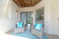 Charming outdoor patio featuring two stylish wicker chairs with turquoise cushions, a modern side table, and lush greenery creating a serene retreat.