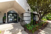 Inviting entrance of the leasing center with modern architecture, lush greenery, and a welcoming atmosphere.