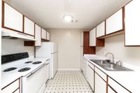 Kitchen with white appliances, wooden cabinetry, and ample counterspace