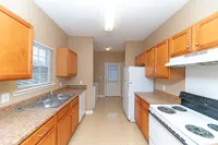Kitchen with white appliances, wooden cabinetry, and generous counterspace