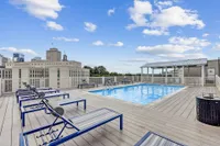 Luxurious rooftop pool area with lounge chairs and stunning city skyline views, perfect for relaxation and leisure.