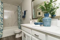 Bright bathroom with granite counters and bathtub with marble backsplash