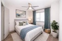 Elegant bedroom featuring a cozy bed with stylish pillows, calming blue curtains, and modern decor, perfect for relaxation.