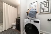 Modern apartment bathroom with elegant marble accents, featuring an in-unit washer and dryer for convenience.