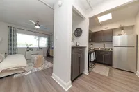 Inviting open-plan apartment with a modern kitchen, cozy living area, and sleek wood flooring, perfect for comfortable urban living.