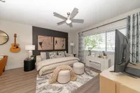 Inviting bedroom with contemporary decor, featuring a cozy bed, modern artwork, and a large window allowing natural light to fill the room.