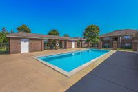 Inviting apartment community with a crystal-clear swimming pool, surrounded by beautiful brick architecture and lush greenery, perfect for relaxation and leisure.
