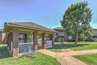 Charming outdoor pavilion and lush green courtyard with a bike and cozy apartment balconies, perfect for relaxing in a vibrant community setting.