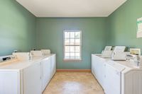Bright and spacious laundry room with multiple modern washing machines and a large window, offering a cheerful and convenient laundry experience.