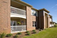 Charming apartment exterior with inviting balconies and well-maintained landscaping under a clear blue sky.