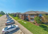 Charming apartment complex with elegant two-story brick buildings, inviting balconies, and well-maintained green spaces, all under a clear blue sky.
