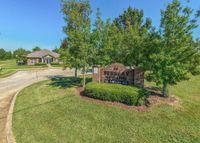 Inviting entrance to Berkeley Spring community with lush greenery and a welcoming sign, leading to a charming brick building.