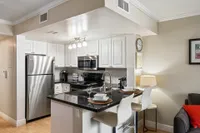 Modern kitchen with sleek stainless steel appliances, elegant black countertops, and cozy bar seating.