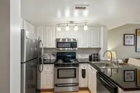 Sleek modern kitchen with stainless steel appliances, glossy black countertops, and elegant white cabinetry.