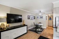 Modern living space with sleek dining set, wall-mounted TV, chic decor, and inviting wooden floors.