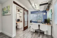 Modern office space featuring sleek furnishings, contemporary art, and a spacious desk area with natural light flooding through large windows.