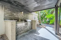 Inviting outdoor BBQ area with sleek stainless steel grills and lush tropical landscaping for a perfect alfresco experience.