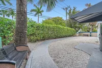 Inviting outdoor space with lush greenery, palm trees, and comfortable seating, perfect for relaxation and enjoying the fresh air.