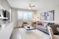 Elegant living area with contemporary decor, featuring a plush sofa, vibrant artwork, and an open concept kitchen with sleek cabinetry.
