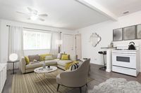 A modern living room with accent chair and couch with yellow accent pillows.