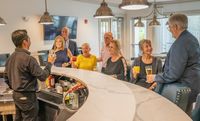Vibrant social gathering in a modern bar setting with cheerful people enjoying drinks and lively conversation.
