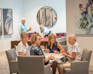 Vibrant social lounge with lively seniors enjoying a game of cards and billiards, creating a welcoming atmosphere for community living.