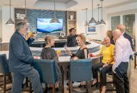 Vibrant community lounge showcasing an elegant bar area with guests enjoying drinks and socializing, highlighted by chic lighting and a large scenic TV display.