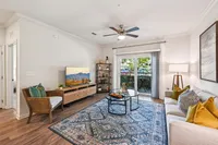 Bright and inviting living room with elegant decor, featuring a spacious sitting area, cozy couch, and stylish accent pieces. Large glass doors open to a serene outdoor patio, perfect for relaxation.