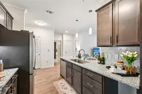 Modern kitchen with sleek granite countertops, stylish dark cabinets, and elegant pendant lighting, creating a welcoming space for cooking and entertaining.