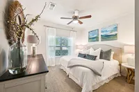 Elegant bedroom featuring a cozy king-sized bed, soft lighting, and tasteful artwork. Natural light flows through large windows, highlighting the serene and stylish decor.
