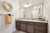 Sleek and modern bathroom with elegant granite countertop, stylish dark wood cabinetry, and luxurious decor.