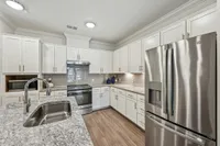 Elegant modern kitchen with stainless steel appliances, sleek granite countertops, and white cabinetry, ideal for culinary enthusiasts.
