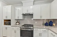 Bright, modern kitchen with sleek white cabinetry, stainless steel appliances, and elegant granite countertops.