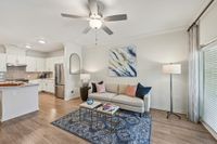 Chic open-plan living area with elegant kitchen and cozy seating, highlighted by a stylish ceiling fan and large windows for natural light.