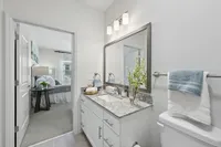Elegant bathroom with granite countertops and modern fixtures, seamlessly connected to a cozy bedroom adorned with tasteful decor.