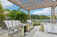 Elegant outdoor barbecue area featuring sleek stainless steel grills under a charming pergola, surrounded by lush greenery for an inviting atmosphere.