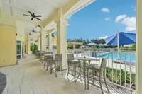 Luxurious poolside patio with elegant seating, ceiling fans, and vibrant blue umbrellas set against a clear sky, perfect for relaxing and enjoying the sunshine.