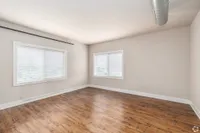 Bright and spacious room with large windows and elegant wood flooring, perfect for customizable living space.