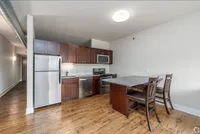 Modern kitchen with stainless steel appliances, cherry wood cabinets, and a sleek granite breakfast bar.