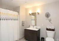 Elegant bathroom featuring a modern vanity with ample storage, stylish mirror, and decorative wall art, complemented by warm lighting and a chic patterned shower curtain.