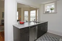 Bright kitchen with granite countertops, sleek dark cabinets, and a window view, seamlessly connected to the elegant dining area.