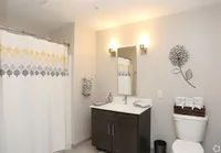 Elegant bathroom featuring a modern vanity, stylish floral wall art, and a chic patterned shower curtain.
