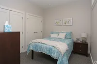 Inviting modern bedroom featuring a cozy bed with stylish blue bedding, elegant artwork, and ample closet space in a serene setting.