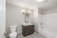Modern bathroom with elegant lighting, sleek vanity, and a pristine bathtub, boasting clean design and functionality.